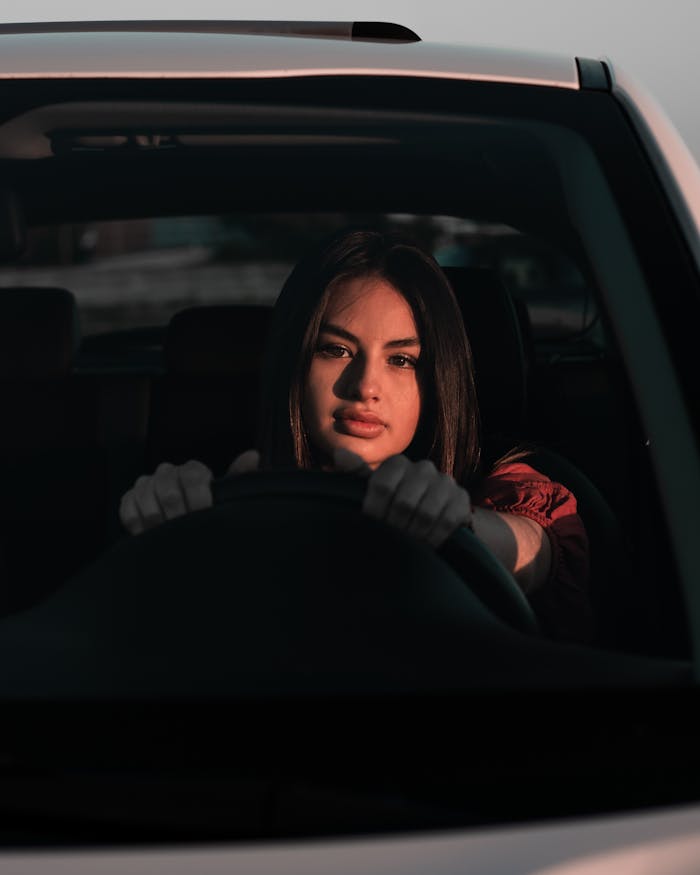 Focused woman driving a car during sunset, emphasizing empowerment and independence.