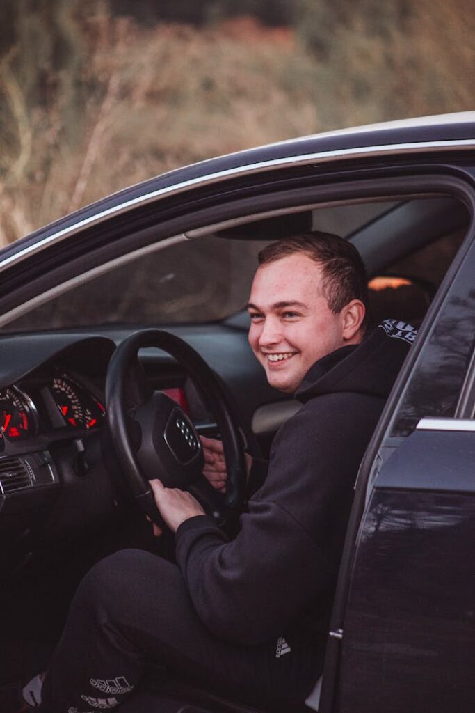 Smiling man in a car enjoying a scenic drive at sunset.